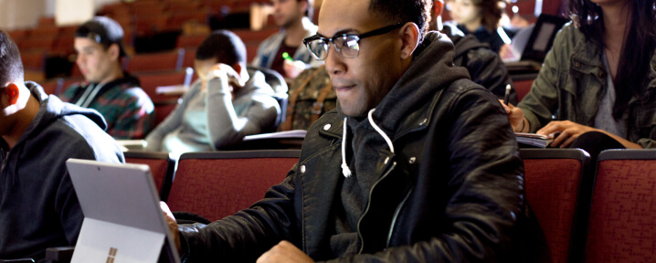 Man in classroom looking at tablet.