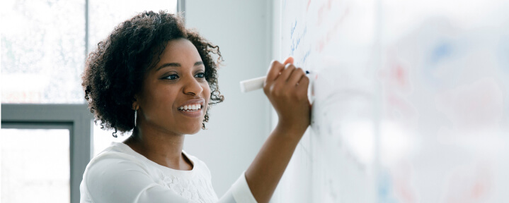 Woman writing on whiteboard.